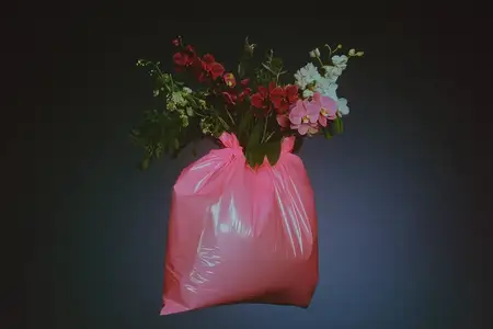 Это яркое изображение представляет собой розовый мешок для мусора, наполненный множеством цветов, что символизирует концепцию экологичности и инноваций в переработке отходов