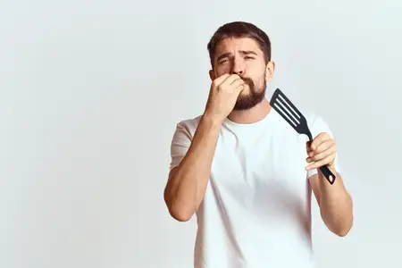 Мужчина с кухонной лопаткой в белой футболке