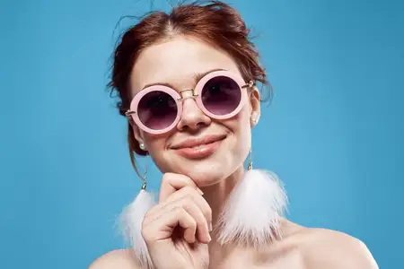 Жизнерадостная эмоциональная женщина в солнцезащитных очках, модная яркая косметика, украшение на синем фоне