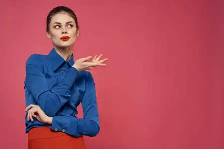 Модная женщина в голубой рубашке на розовом фоне, красная юбка, эмоции, модель жестикулирует руками, обрезанный вид, свободное пространство