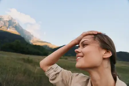 Светло-бежевая рубашка в сельском пейзаже, наслаждающаяся солнцем и свежим воздухом, глядя на горизонт спокойным, уверенным взглядом, в обрамлении открытого поля и далеких вершин