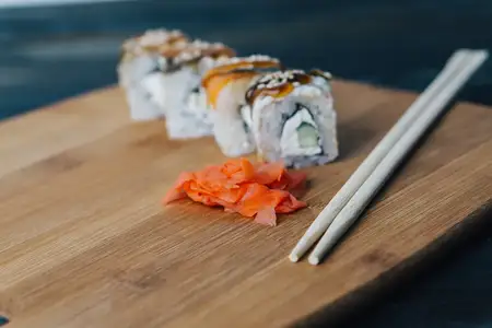 Роллы суши, красный имбирь, палочки, деревянная доска, крупный план