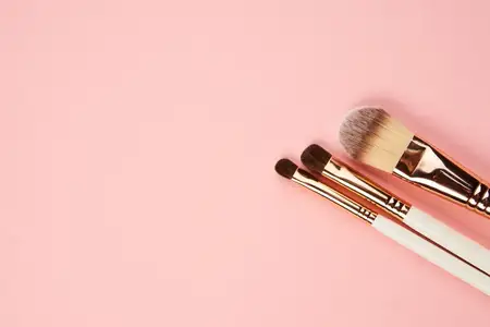 Кисти для макияжа и тени для век, профессиональная косметика на розовом фоне