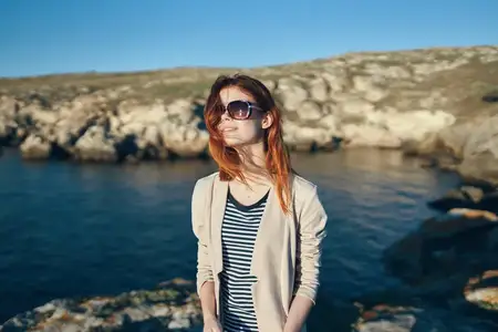 Женщина-туристка в футболке и очках на природе в горах