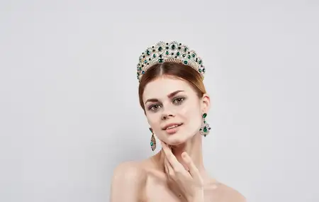Красивая женщина с обнажёнными плечами, украшениями и косметикой, привлекательный взгляд, изолированный фон