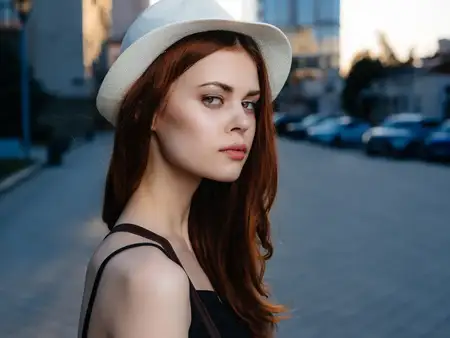 Симпатичная женщина в шляпе позирует на улице летом