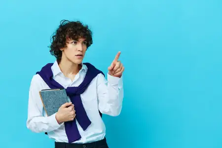 Кудрявый парень с блокнотом, на плечи накинута рубашка-свитер, стиль жизни, школа