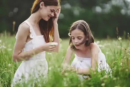 Мама и дочь в поле на природе весело собирают цветы