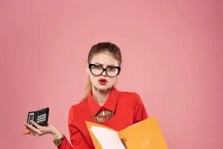 Бизнес-леди в красной рубашке и очках с документами в руках работает в офисе
