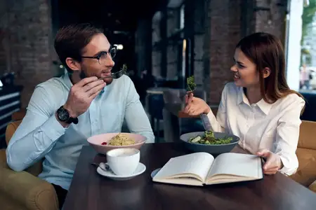 Мужчина и женщина, коллеги по работе, завтракают в кафе и общаются