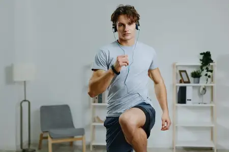 Мужчина в наушниках занимается спортом дома