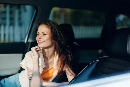 Молодая женщина с длинными волосами улыбается, сидя в автомобиле