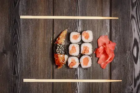 Роллы с морепродуктами на деревянном столе рядом с палочками для еды
