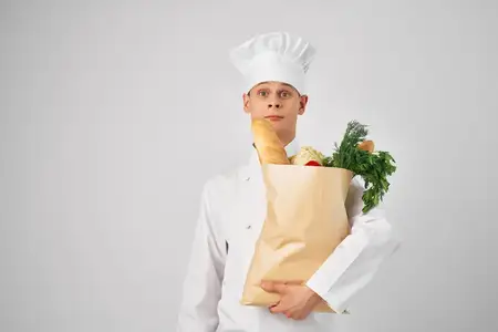 Эмоциональный мужчина-шеф-повар с пакетом продуктов
