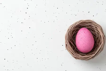 Розовое крапчатое пасхальное яйцо, лежащее в плетеном гнезде, на белом крапчатом фоне
