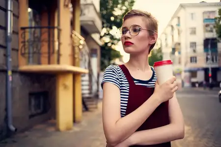 Женщина с короткой стрижкой на улице с чашкой напитка, образ жизни