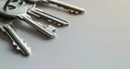 На изображении несколько металлических ключей, собранных вместе и лежащих на нейтральном текстурированном фоне, что подчеркивает их дизайн и функцию