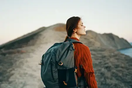 Женщина-туристка в горах на фоне приключений на открытом воздухе: рюкзак, тропа, модель