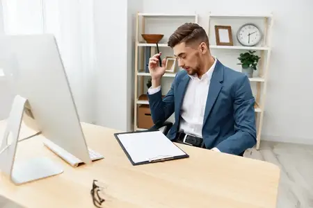 Мужчина в костюме сидит за компьютером, работая с документацией, как начальник, на сером фоне