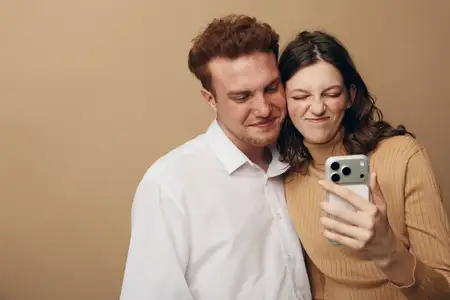 Счастливая молодая пара в повседневной одежде делает селфи со смартфоном