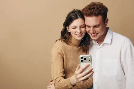 Молодые мужчина и женщина улыбаются, делая селфи на мобильный телефон