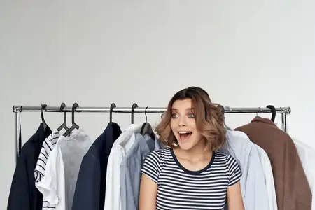 Веселая женщина рядом с одеждой, мода, веселье, светлый фон