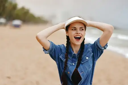 Счастливая молодая женщина, улыбающаяся девушка, летнее настроение: портрет привлекательной леди, отдыхающей на пляже во время отпуска
