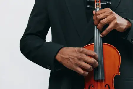 Крупный план мужчины в костюме, играющего на скрипке на белом фоне