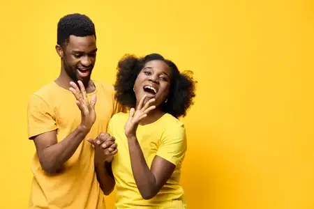 Яркая, счастливая африканская пара в желтом, демонстрирующая радость и игривость