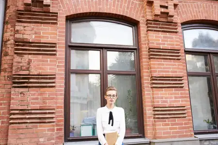 Студент в очках прогуливается по городу с книгой