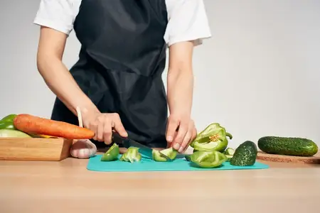 Повар на кухне нарезает овощи, наполненные витаминами, занимаясь домашними делами