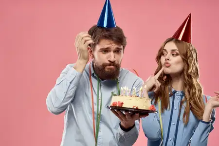 Мужчина и женщина на вечеринке с тортом на розовом фоне