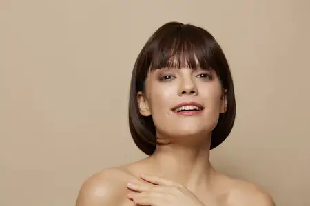 Женщина с обнаженными плечами и чистой кожей, позирует на изолированном фоне