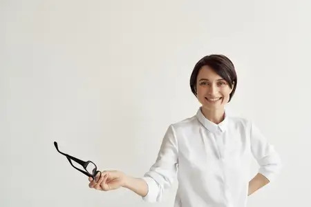 Женщина в белой рубашке и очках, уверенная в себе, на изолированном фоне