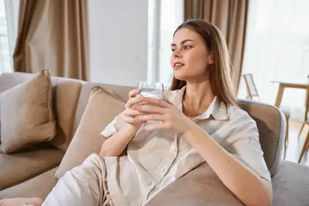 Женщина отдыхает на диване со стаканом воды