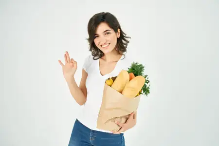 Женщина с пакетом продуктов, совершающая покупки овощей для доставки
