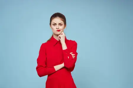 Привлекательная женщина в яркой одежде на голубом фоне жестикулирует руками, макияж с красными губами, обрезной вид, эмоции