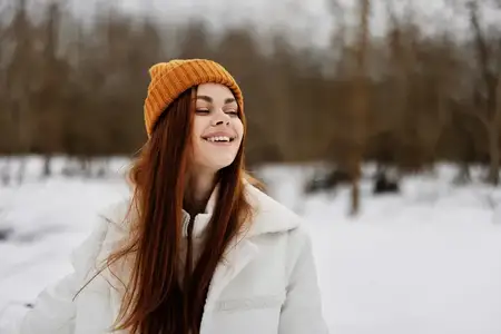 Женщина в зимней одежде и шапке на фоне весёлого зимнего пейзажа
