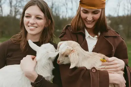 Яркая сцена на открытом воздухе: рядом находятся козы, улыбающиеся спутники разделяют теплую связь