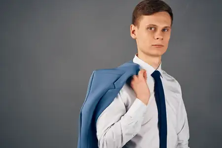 Бизнесмен в рубашке с галстуком, пиджак на плече, излучает уверенность в себе в офисе