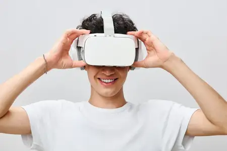 Молодой человек радостно погружается в виртуальную реальность в стильном VR-шлеме на светлом фоне
