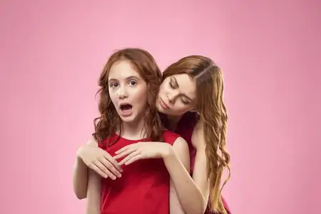 Веселая мама и дочь в красных платьях стоят рядом с радостной семьей на розовом фоне