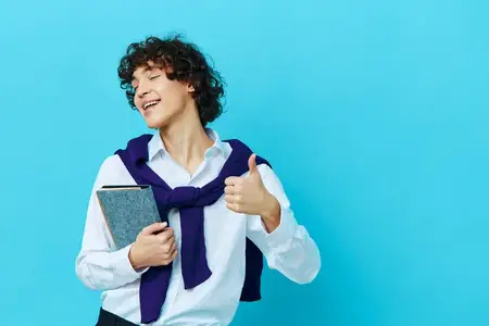 Кудрявый парень с блокнотом, в свитере, накинутом на плечи, на синем фоне