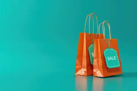 На бирюзовом фоне лежат пакеты для покупок с бирками распродажи, что символизирует модные тенденции и деловые возможности