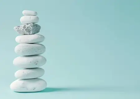 Безмятежная композиция из белых камней, уравновешенно сложенных друг на друга на успокаивающем бирюзовом фоне, олицетворяет покой и осознанность в дизайне