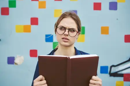 Удивленная студентка в очках на улице с книгой, эмоции, модель
