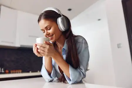 Молодая женщина наслаждается музыкой и кофе в уютной домашней обстановке на своей кухне — это расслабляющий момент блаженства