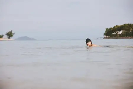 Активный азиатский мужчина наслаждается летними брызгами воды во время отпуска на тропическом пляже