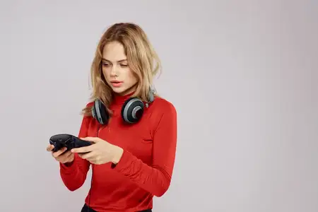 Женщина в наушниках с контроллером в руках, консольная игра, отдых, красная куртка, образ жизни, светлый фон