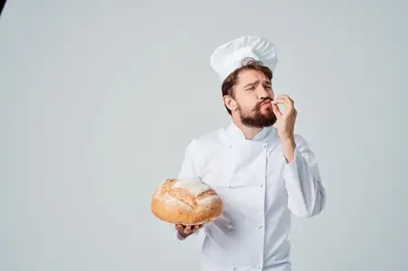 Бородатый мужчина-шеф-повар занимается выпечкой на светлом фоне
